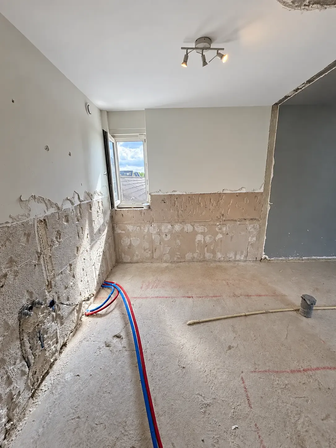 Een badkamer na verwijdering van sanitair en wandtegels.