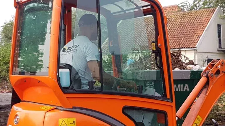 Een machinist aan het werk in een compacte graafmachine.